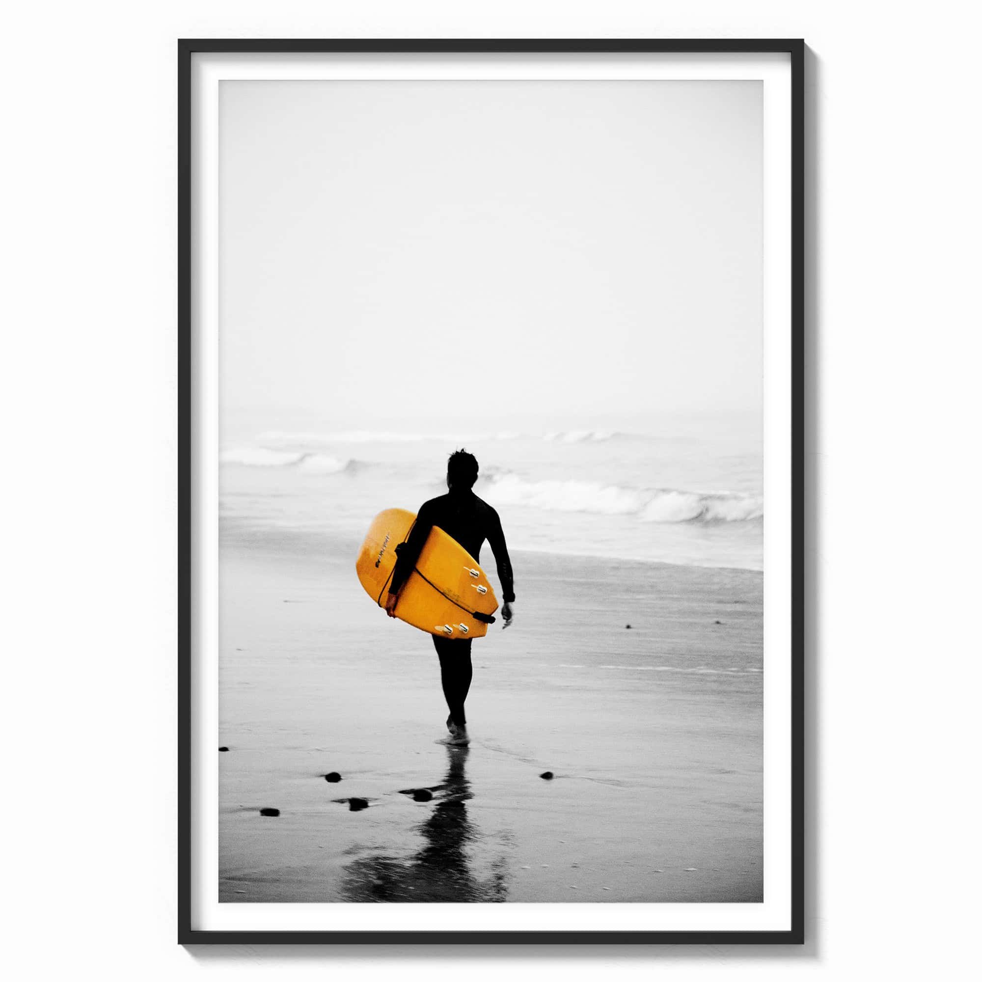 This stunning wall art features a lone surfer, poised with a vibrant yellow surfboard, heading towards the misty ocean waves in a black wood frame.