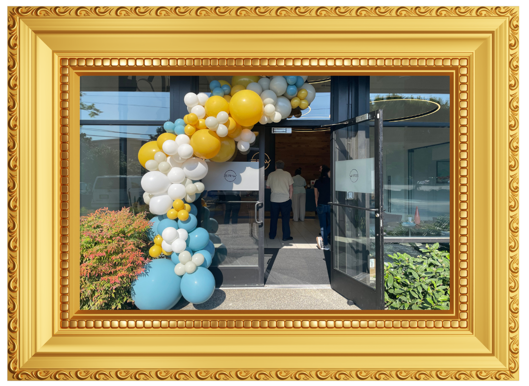 Entrance decorated with colorful balloons, including yellow, white, light blue, and dark blue, leading into a building with several people inside.