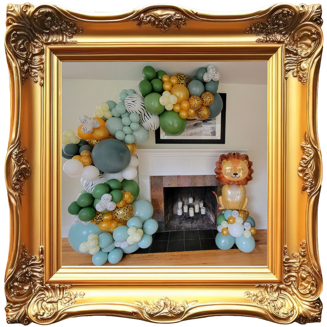 Decorative balloon arrangement in front of a fireplace with a lion balloon figure on the right, inside a gold ornate frame.