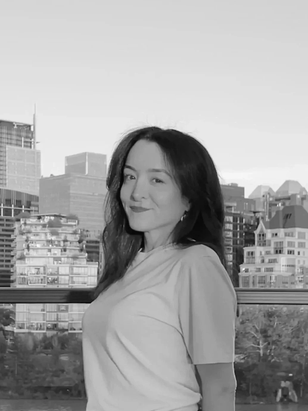 Portrait photo depicting Alice in a white tshirt with skyline background, in black and white.