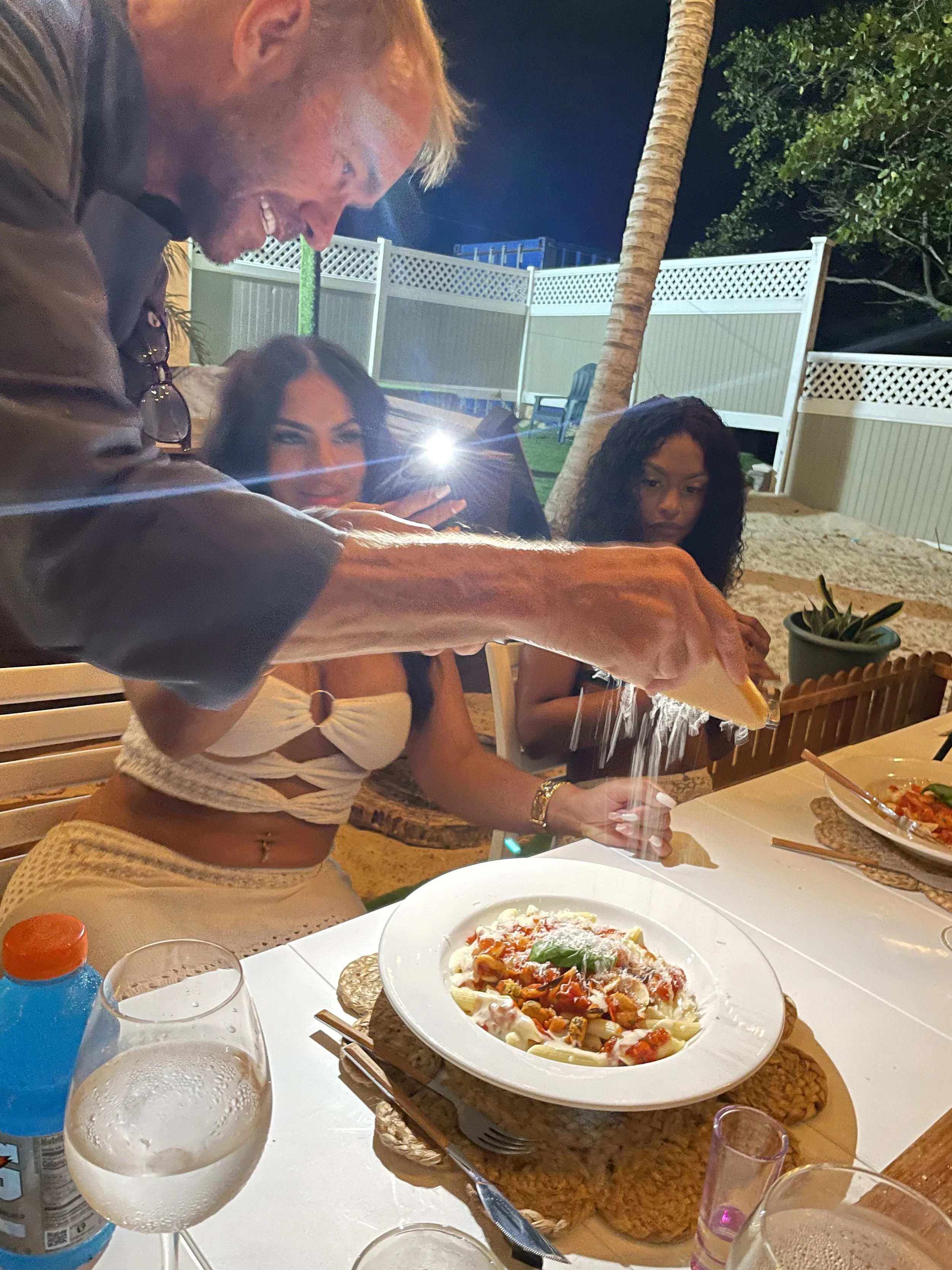 Grating parmesan cheese over a freshly cooked Italian private dinner Aruba.