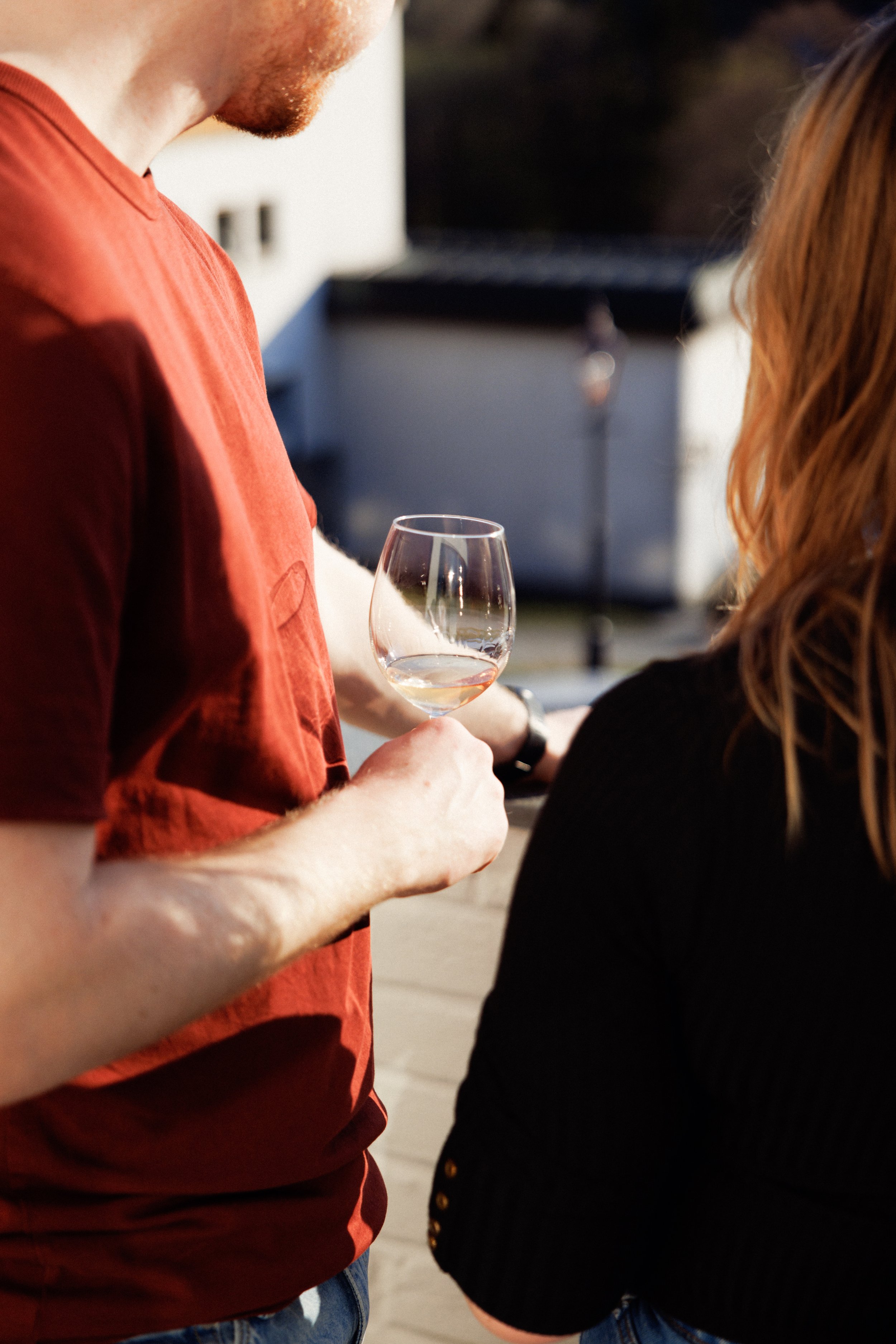 To personer holder et vinglass med hvitvin utendørs på dagtid.