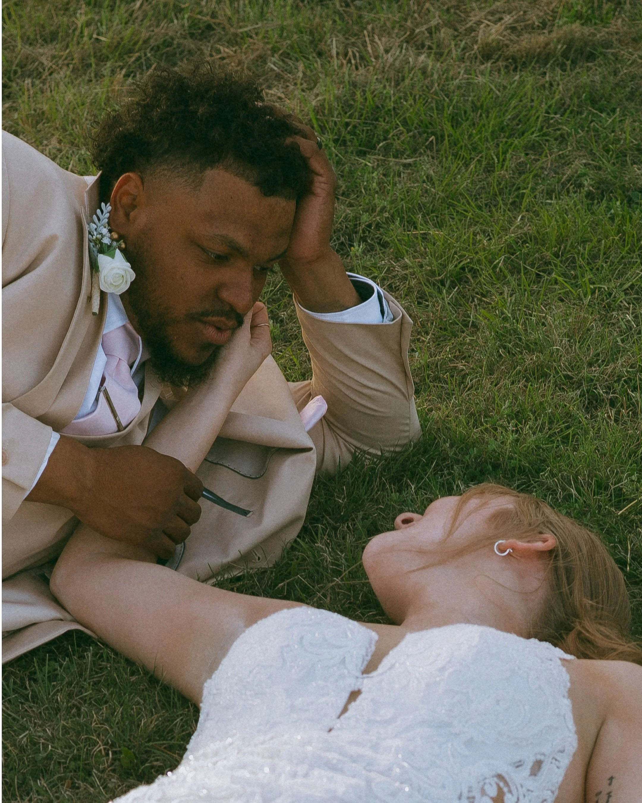 Bride and groom lying together in the grass during documentary wedding portraits