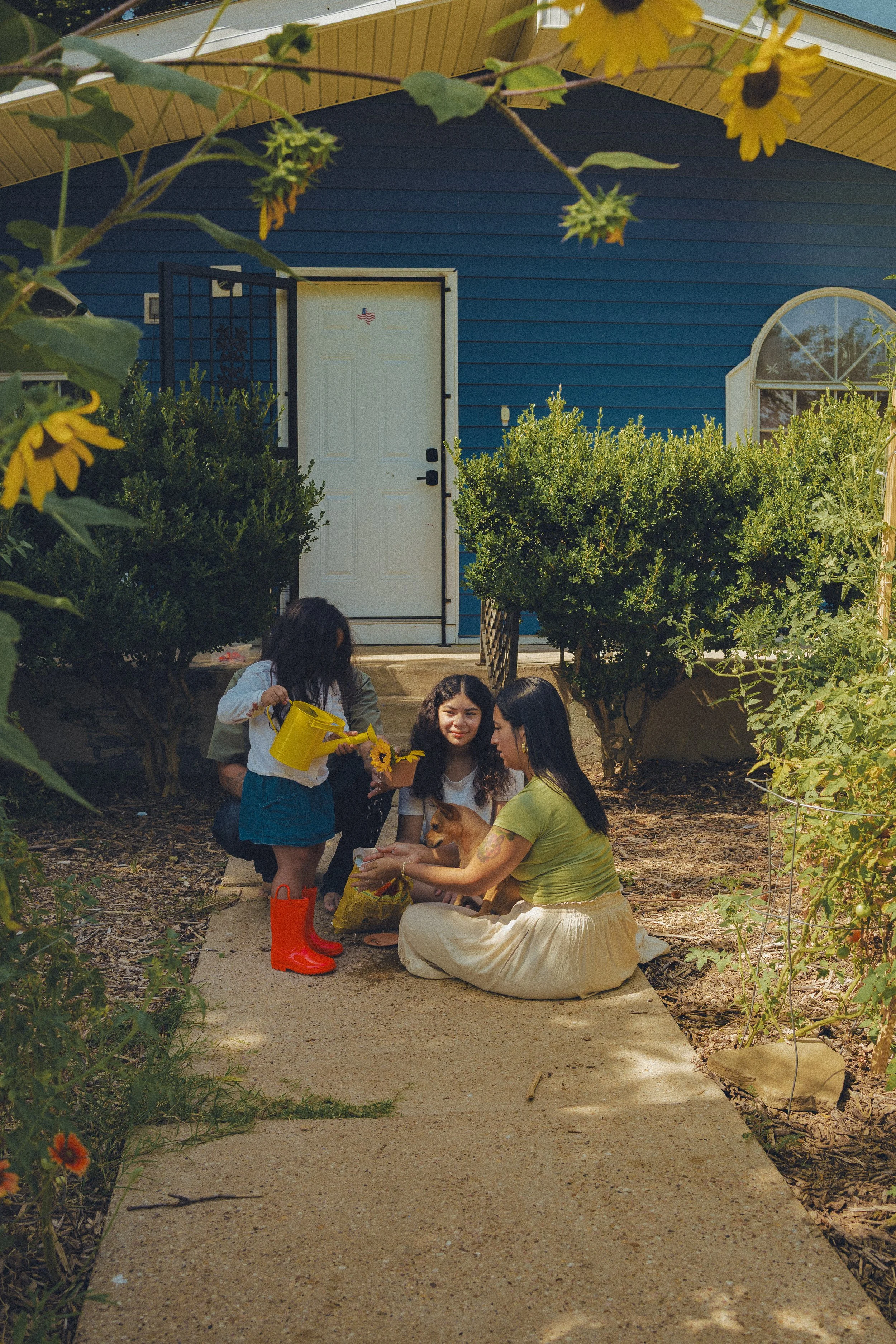 A family session in the garden, with hoseplay, an orange kitten, and fresh produce.