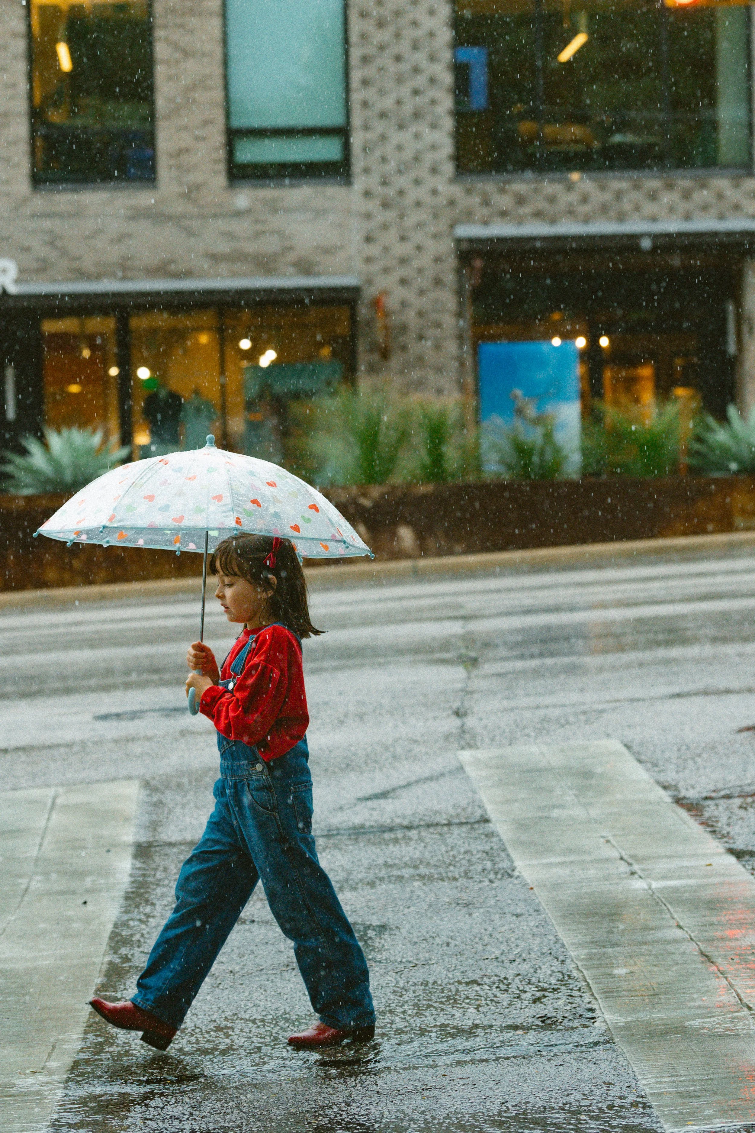 A family playing together beneath colorful umbrellas on a rainy day