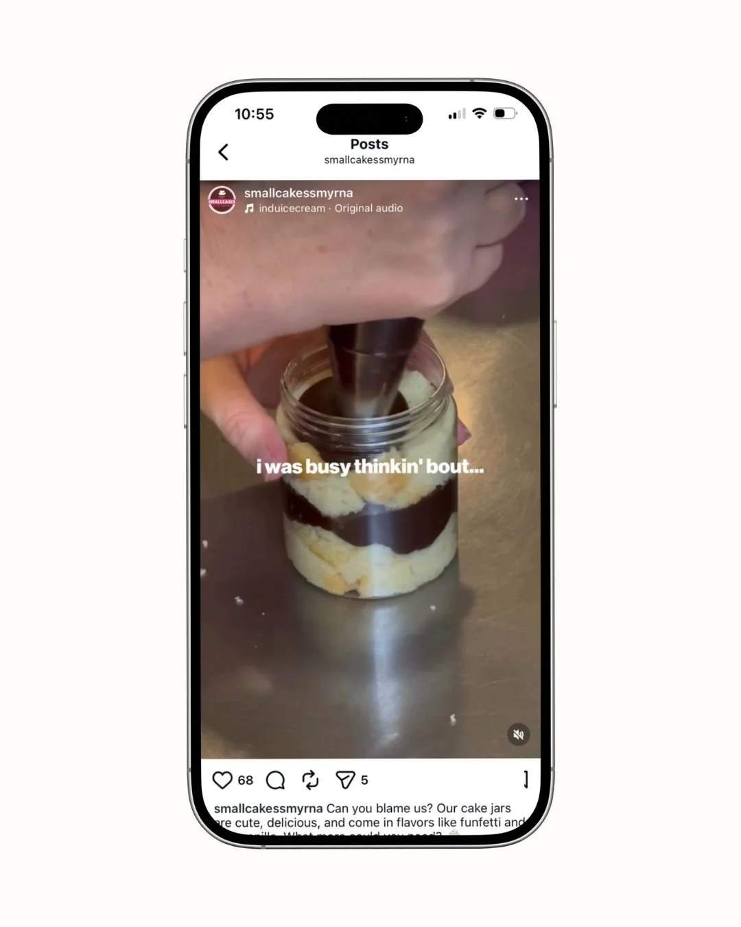 Close-up of a person using a piping bag to put chocolate onto a cake jar with layered cake inside.