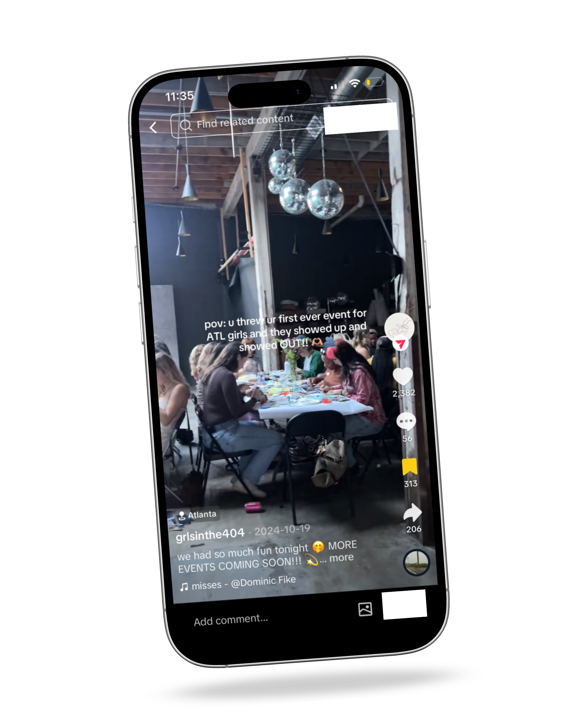 A group of women gathered around a long picnic table at an indoor event space with wood beams and hanging disco balls.