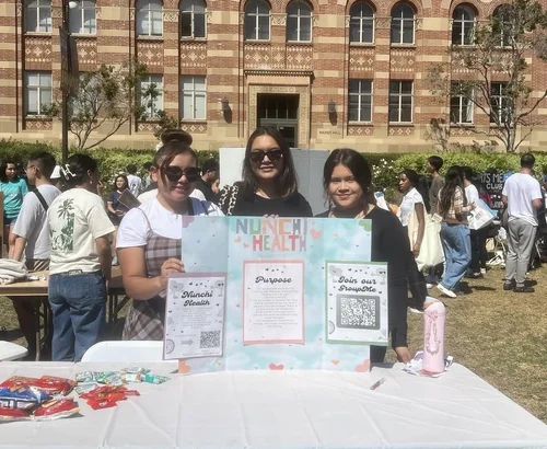 Our campus chapter leaders standing in front of an open table with an tri-folded display board as they unreveal Nunchi Health to their university!