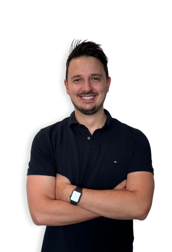 A smiling man with short dark hair and a beard, wearing a navy blue polo shirt and a smartwatch on his left wrist, standing with arms crossed against a black background.