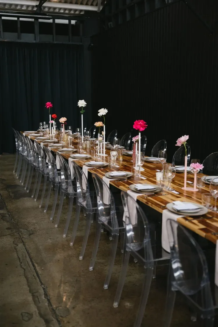 Long reception table styled with colourful florals, candlelight and modern glassware at The Refinery in Brisbane.