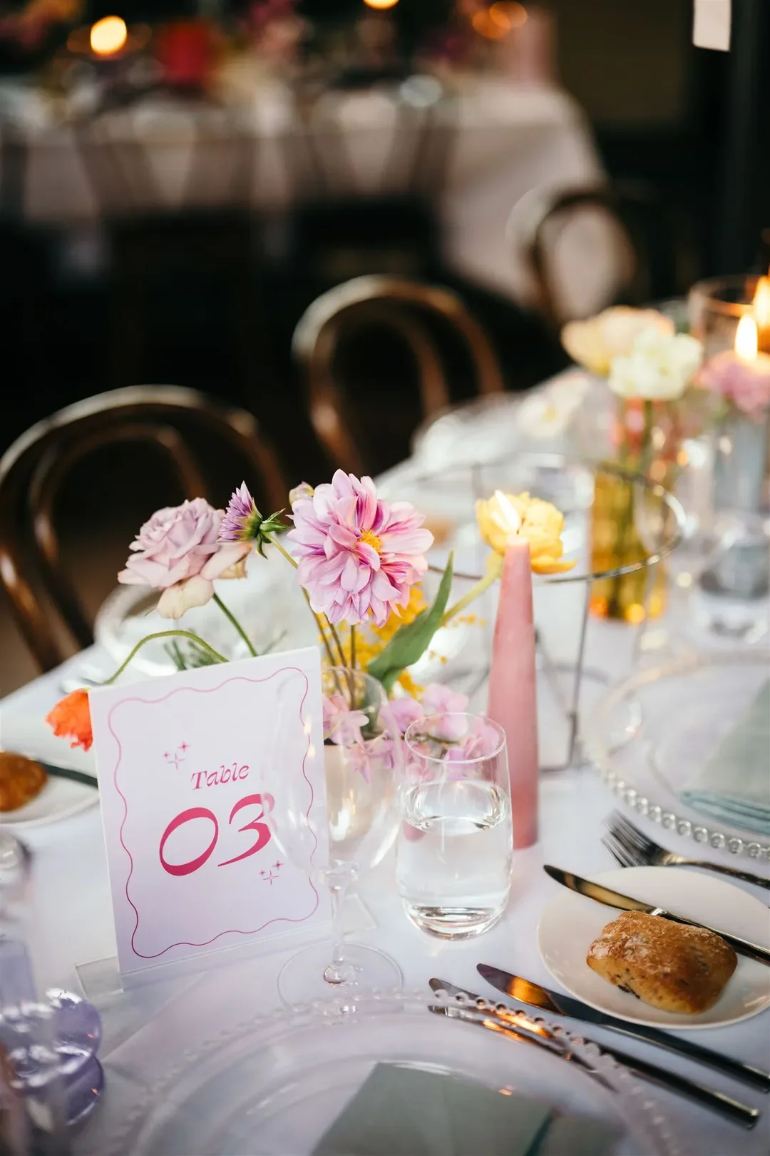 Wedding reception table setting decorated with delicate florals, candles, and modern tableware for Sarah and Marshall’s celebration.