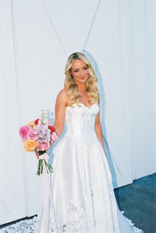 Bride holding a vibrant bouquet against a white backdrop, showcasing Garden Graffiti wedding florals