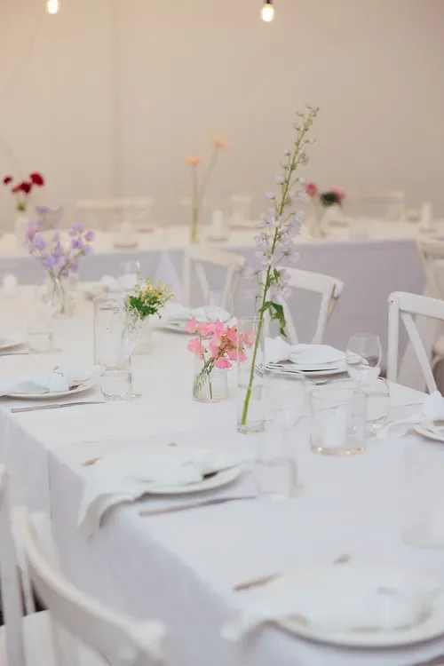 Bright, airy wedding reception tables styled with soft pastel florals and warm lighting