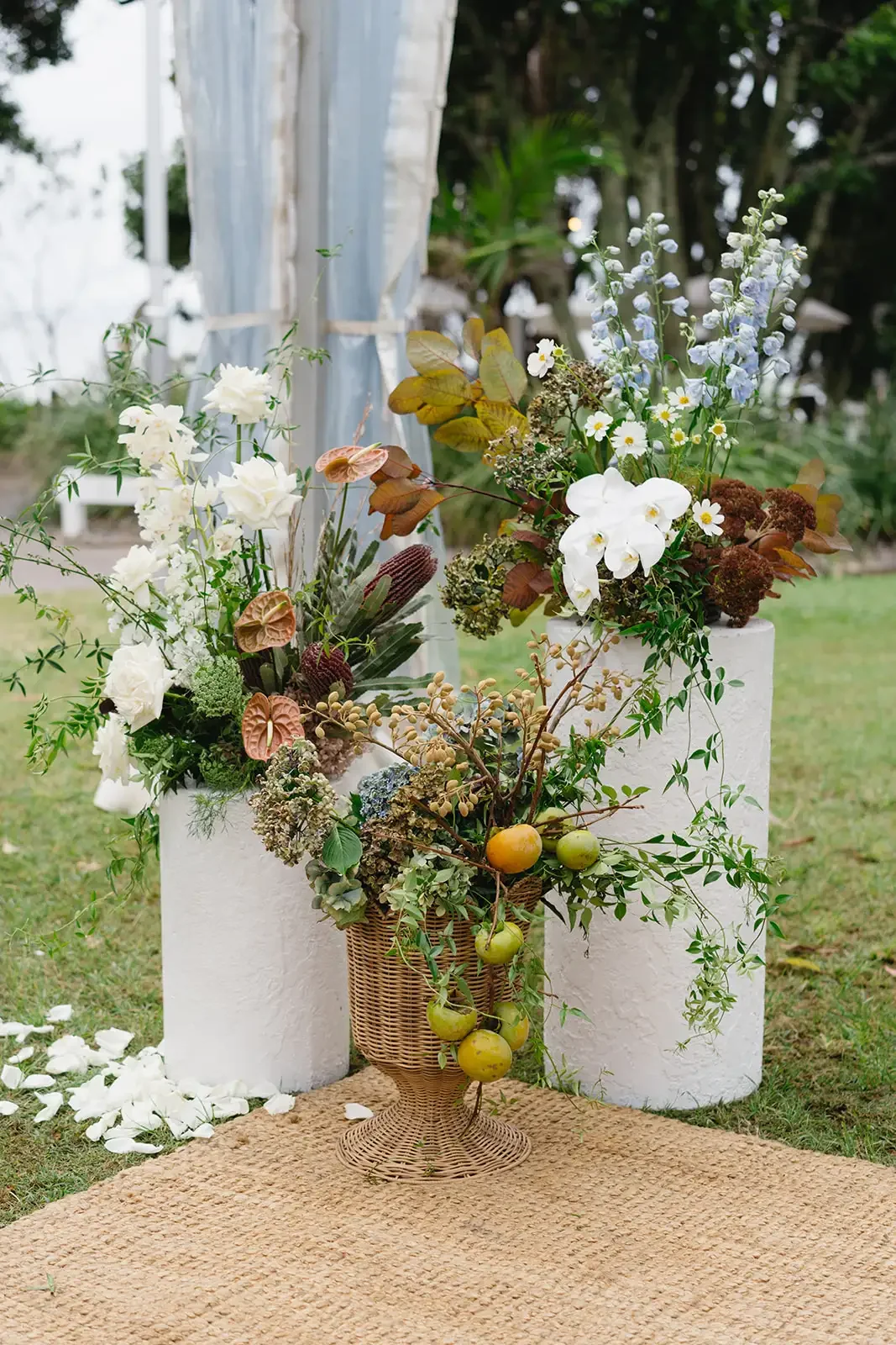 Close-up of natural ceremony florals with white orchids, delphinium, roses and textured foliage.