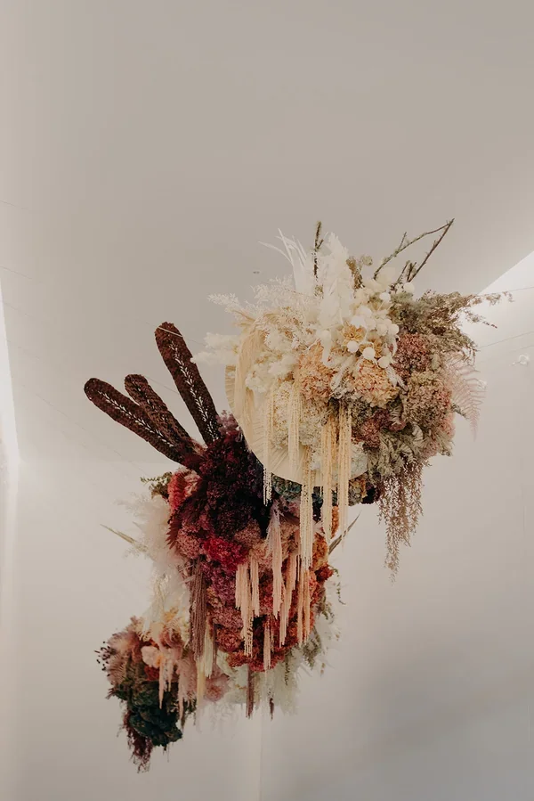 Garden Graffiti florist installing ferns, hydrangea, and hanging florals on the large suspended structure at West Village.