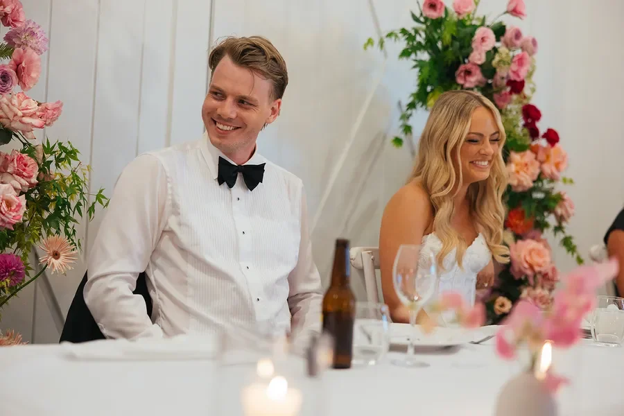 Bride and groom seated at the reception table surrounded by colourful Garden Graffiti floral designs