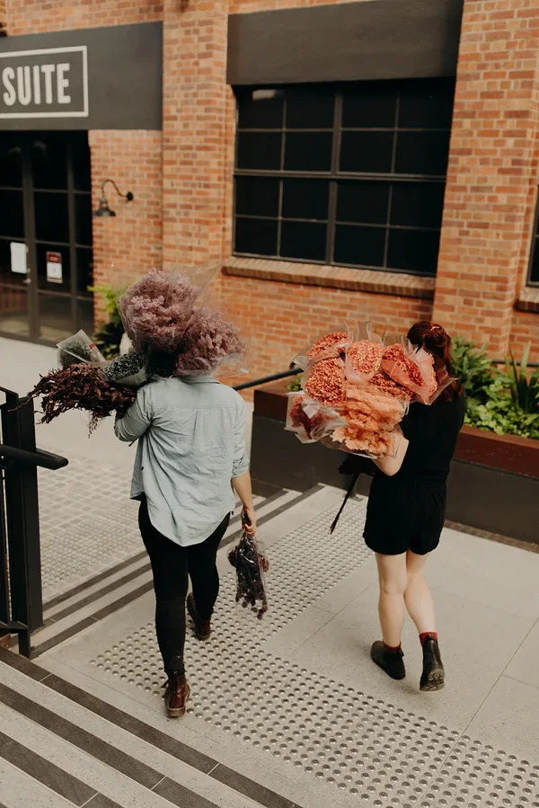 Garden Graffiti florists carrying bundles of dried flowers and materials into West Village for the corporate installation.