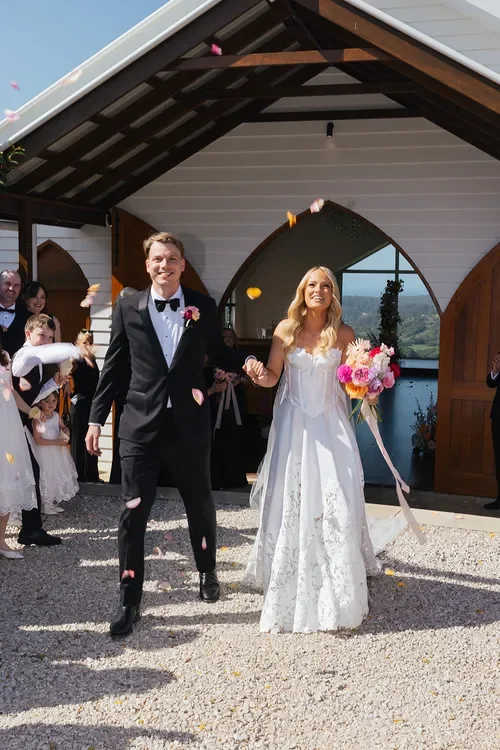 Newlyweds walking back down the aisle as guests throw petals outside a chapel wedding