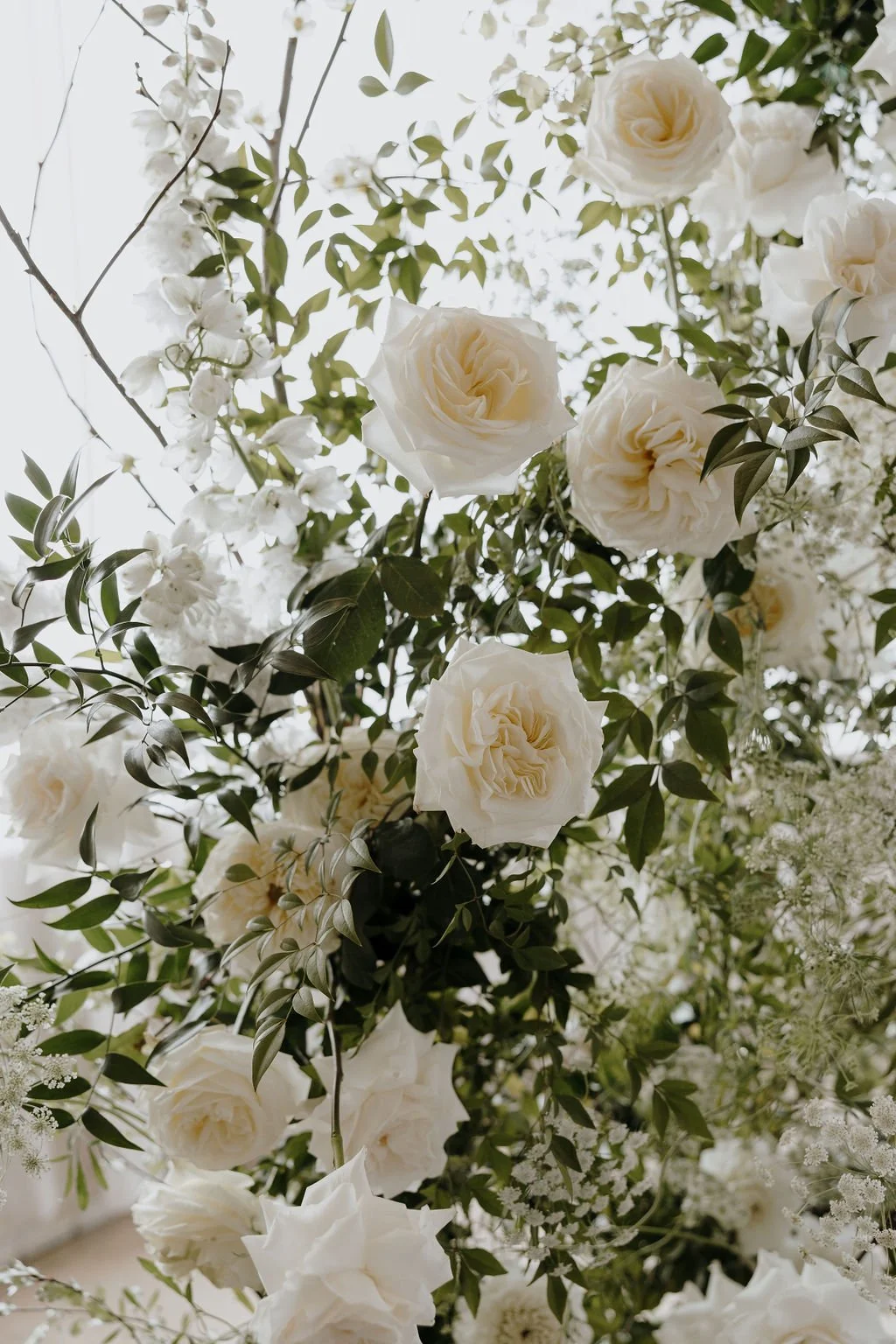Close-up of white roses and delicate greenery from the wedding floral installation.