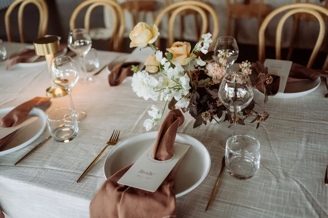 Close up shot of a table floral arrangement with brown napkin and personalised menu
