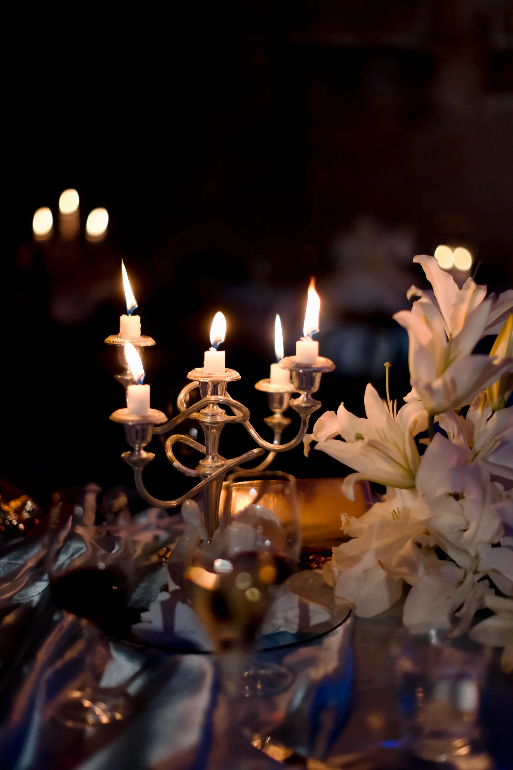 Candlelit reception table with white lilies and a silver candelabra