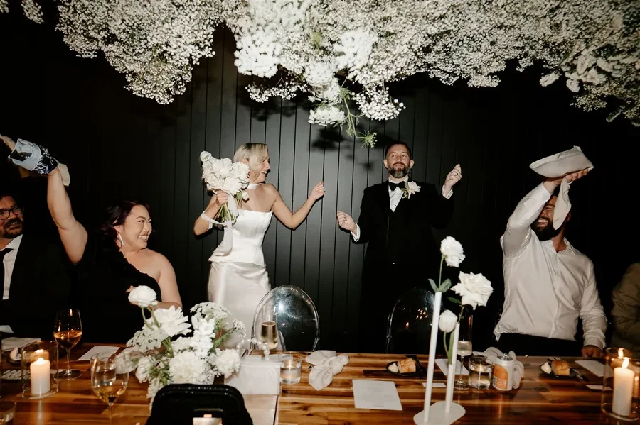 Bride and groom celebrating during wedding reception beneath hanging florals at The Refinery Brisbane