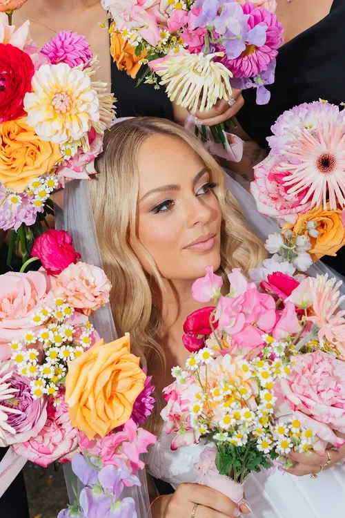 Bride surrounded by colourful Garden Graffiti bridal bouquets featuring pink, peach, and soft pastel blooms