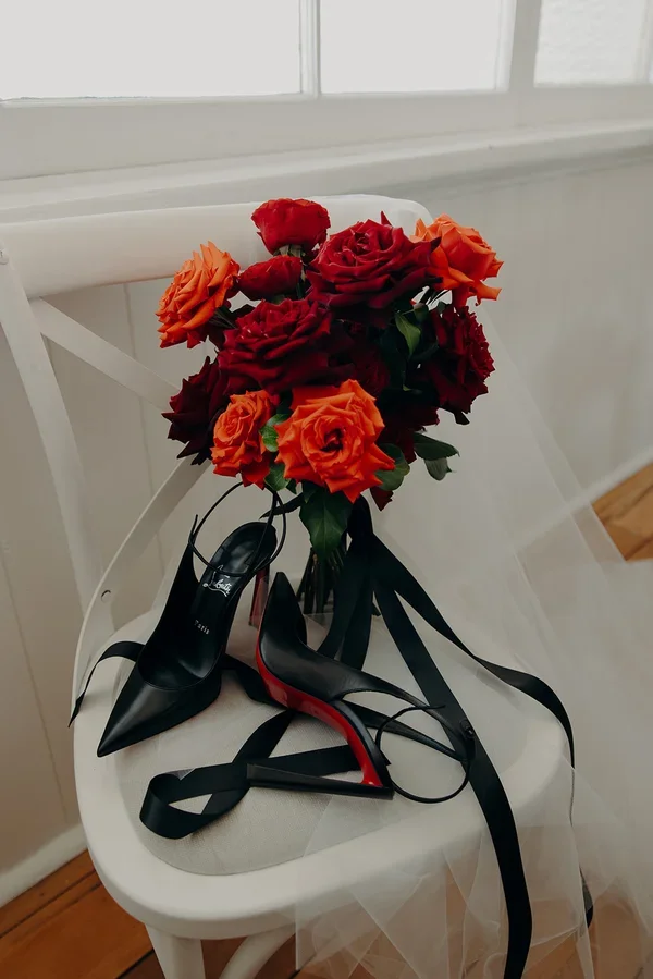 Bride’s modern wedding details featuring deep red bouquet, black heels and dramatic romantic styling.