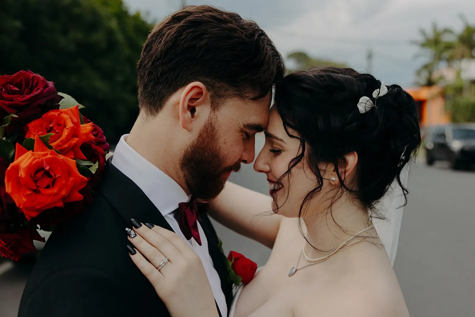 newlywed couple after Brisbane wedding with red rose bouquet and buttonhole