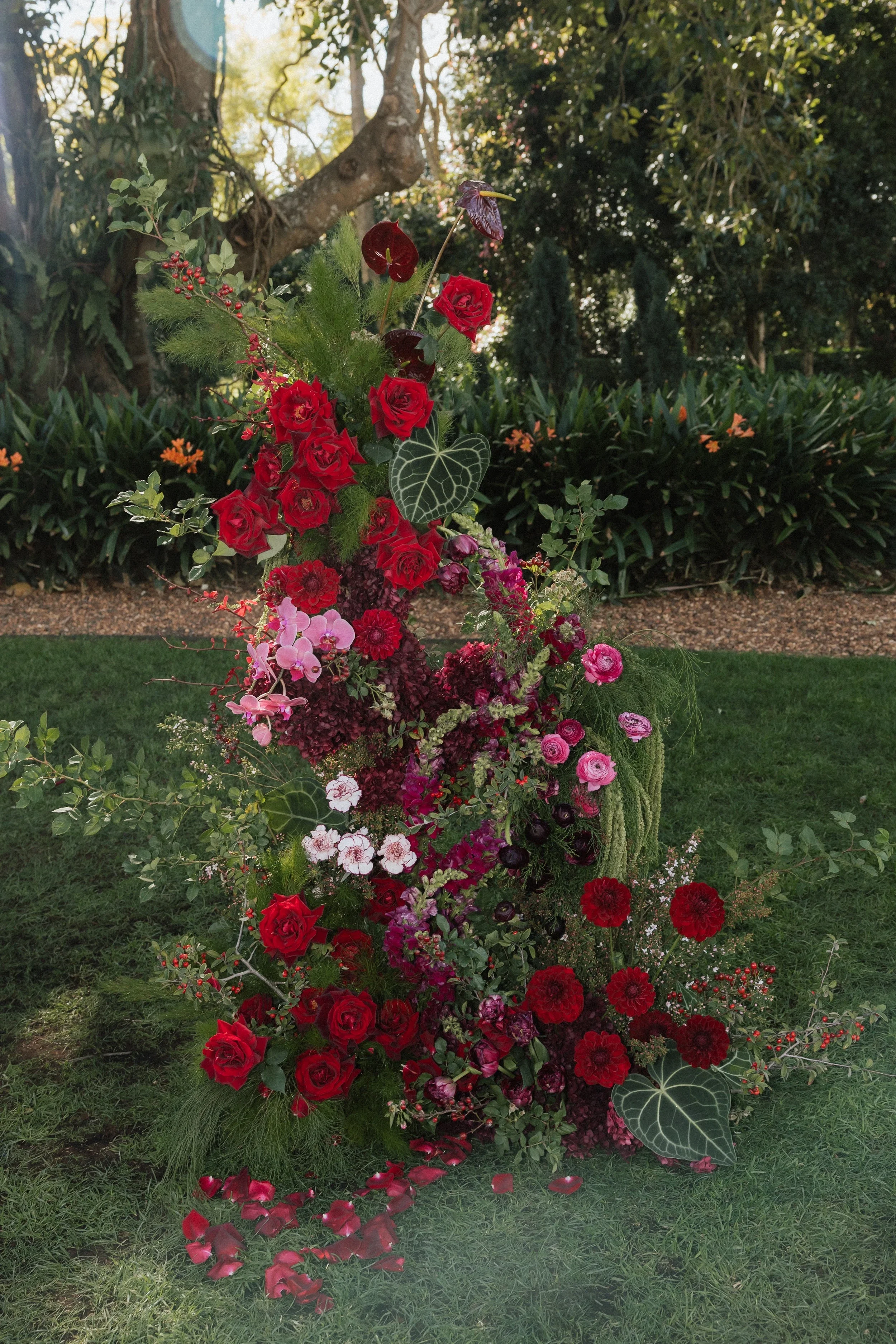 Ceremony floral column of deep red roses, dahlias and pink blooms on the lawn at Gabbinbar