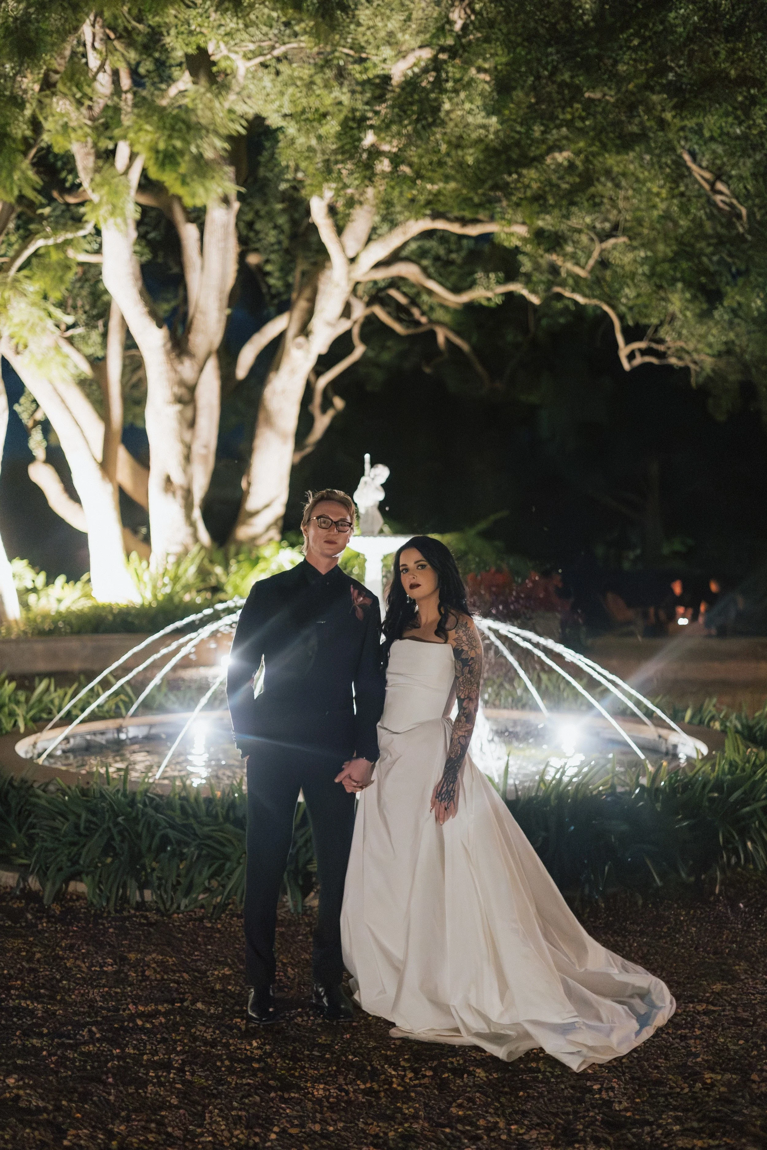 Bride and groom at night beside a lit fountain under the trees at Gabbinbar Homestead