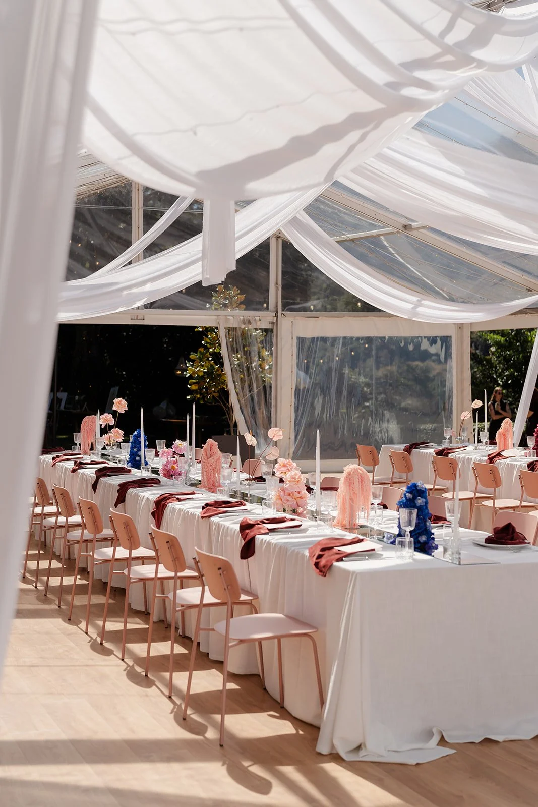 Sunlit marquee with draping and long tables full with florals and styling