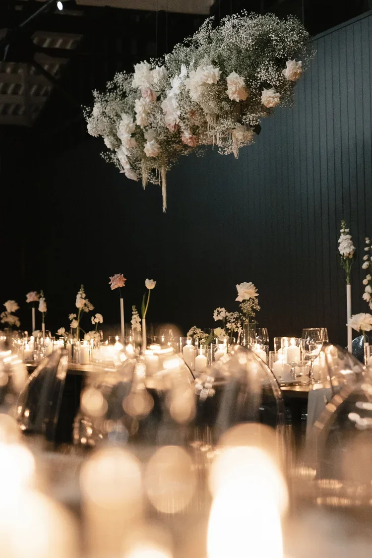 Dramatic hanging installation of white and blush flowers and baby’s breath above long timber reception tables.