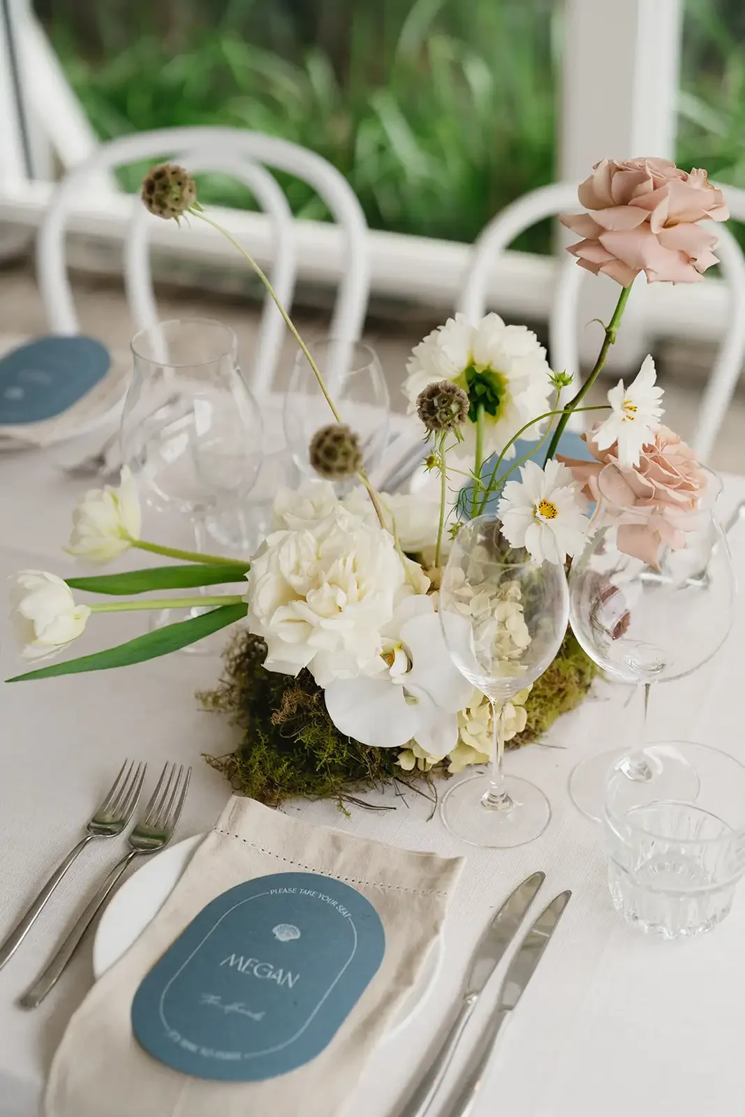 Wedding reception table decor with white and blush florals, moss and minimalist place settings.