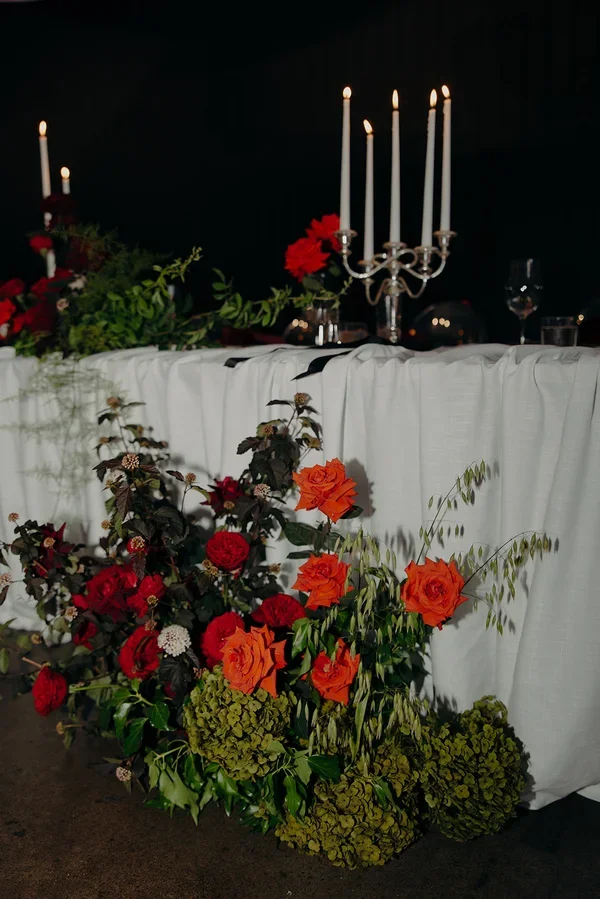 Close-up of rich red roses and deep-toned foliage used in the ceremony floral design.
