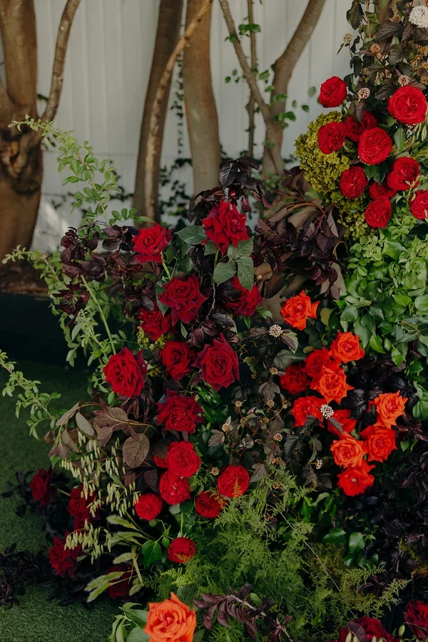 Close-up of rich red roses and deep-toned foliage used in the ceremony floral design.