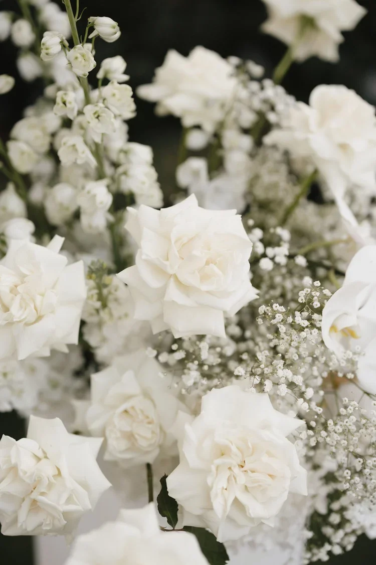 Close-up of lush white roses and baby’s breath arranged in an elegant wedding floral design.