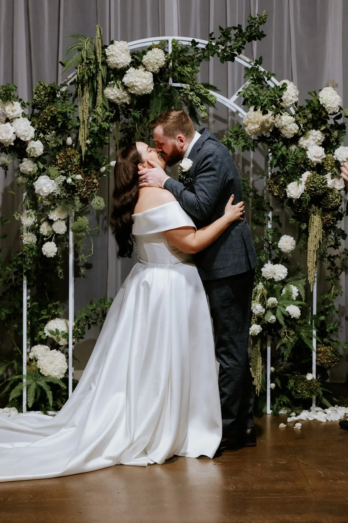 newlywed couple kissing under floral arbour at Brisbane wedding