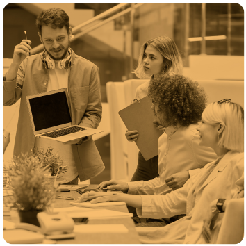 Group of professionals in a business meeting, one holding a laptop, others engaged in discussion.