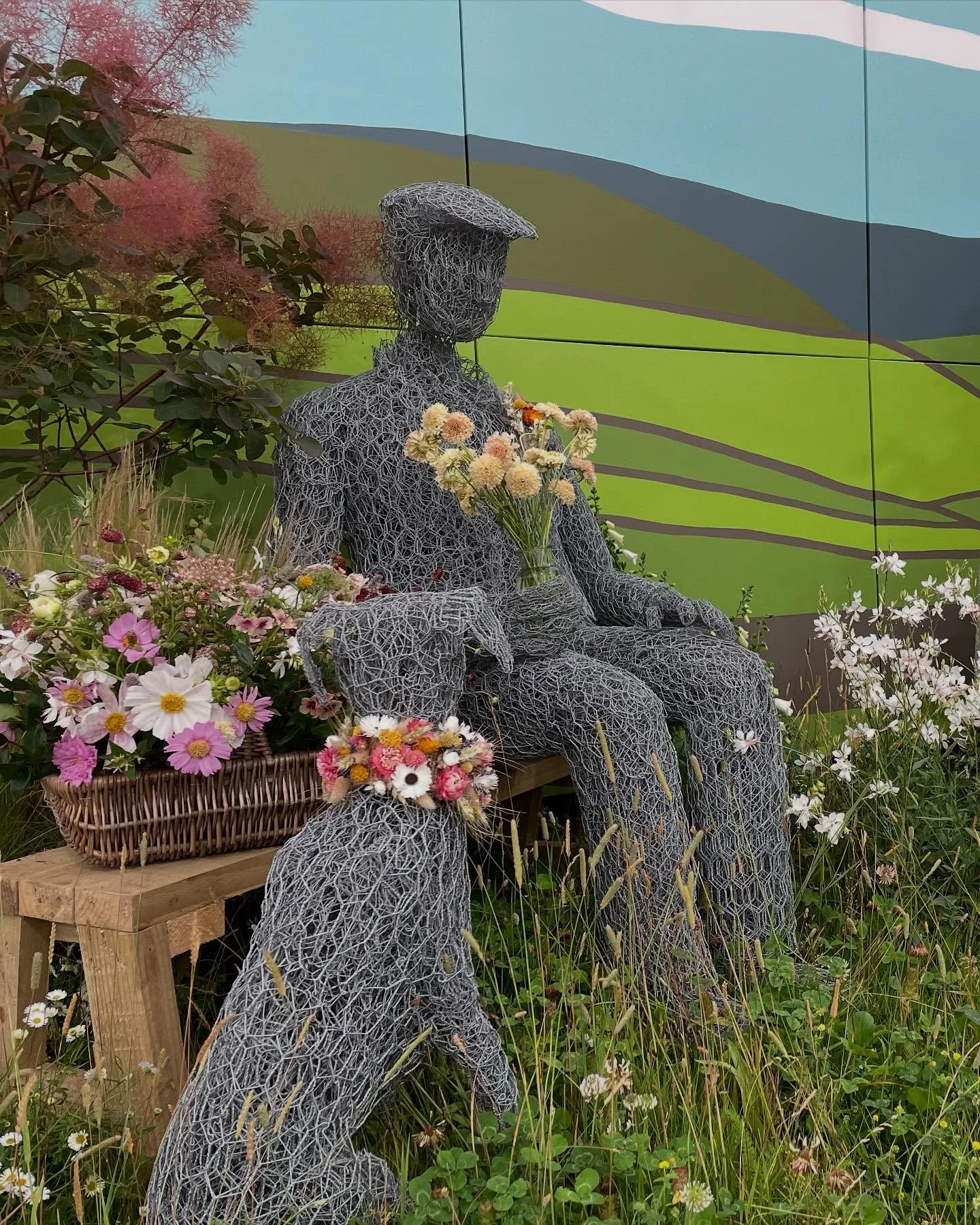 . 
An award-winning display at an RHS show is never the work of just one person.
Here, Yorkshire sculptor, Susan Nichols wire man and his dog rest infront of Adam Clark&rsquo;s @adammdclark backdrop of the Yorkshire Dales.
&lsquo;Harold&rsquo; is hol