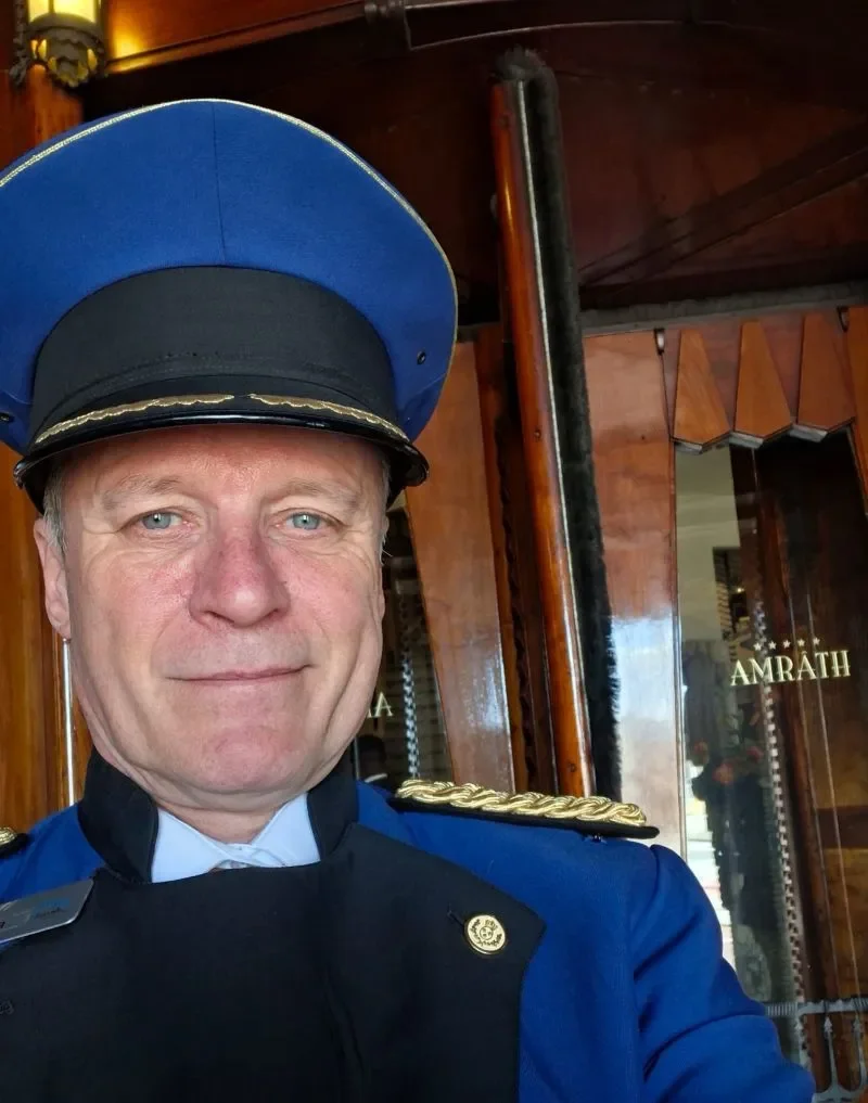 ZilverWerker Robert in portiersuniform vóór de monumentale draaideur van Grand Hotel Amrâth in het Scheepvaarthuis, Amsterdam.