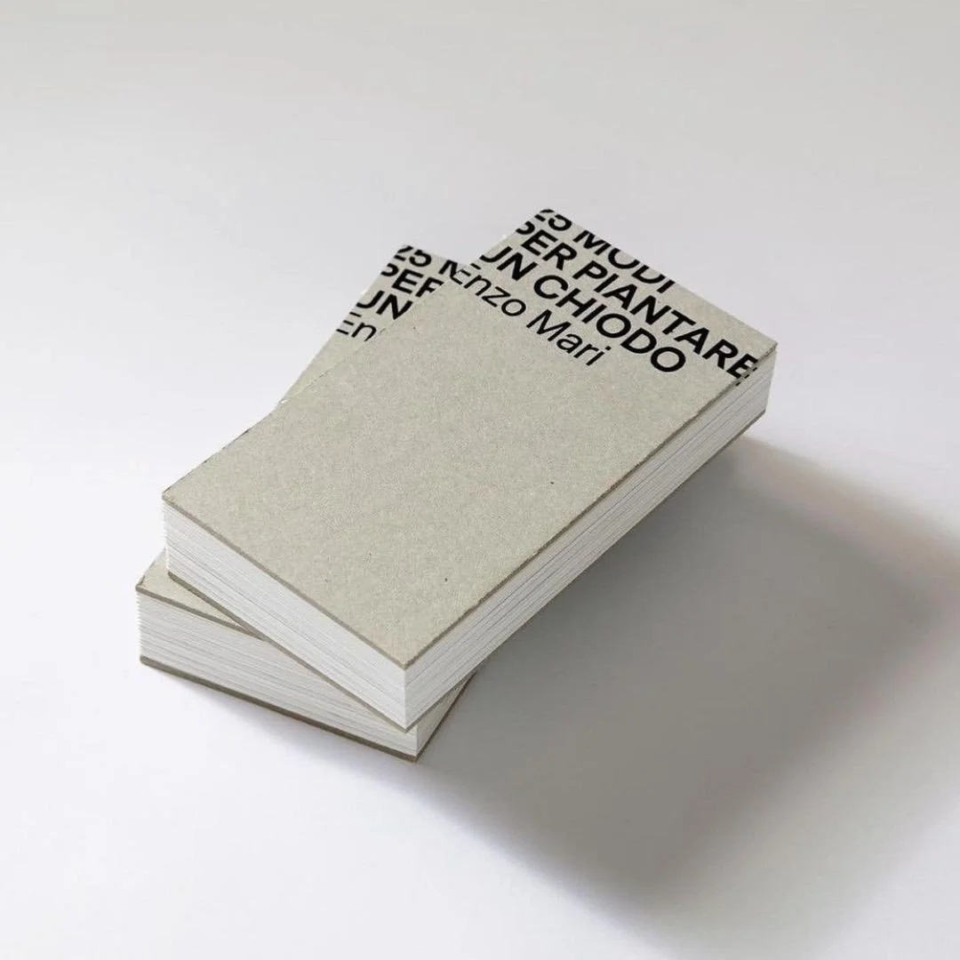 Deux livres empilés avec couverture minimaliste, texte en italien visible, sur surface blanche.