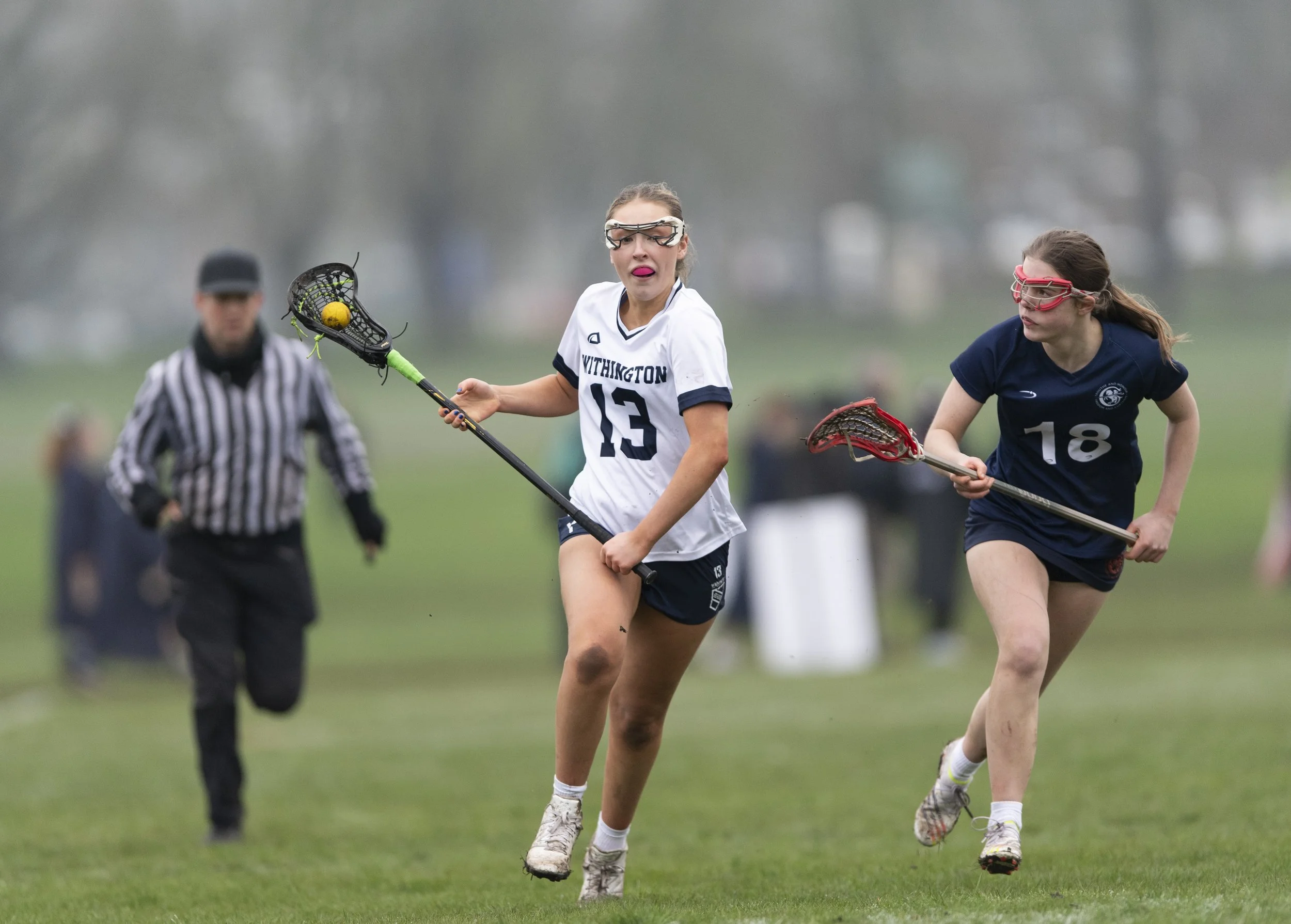 Withington Girls' School player runs with ball in stick next to opposition player