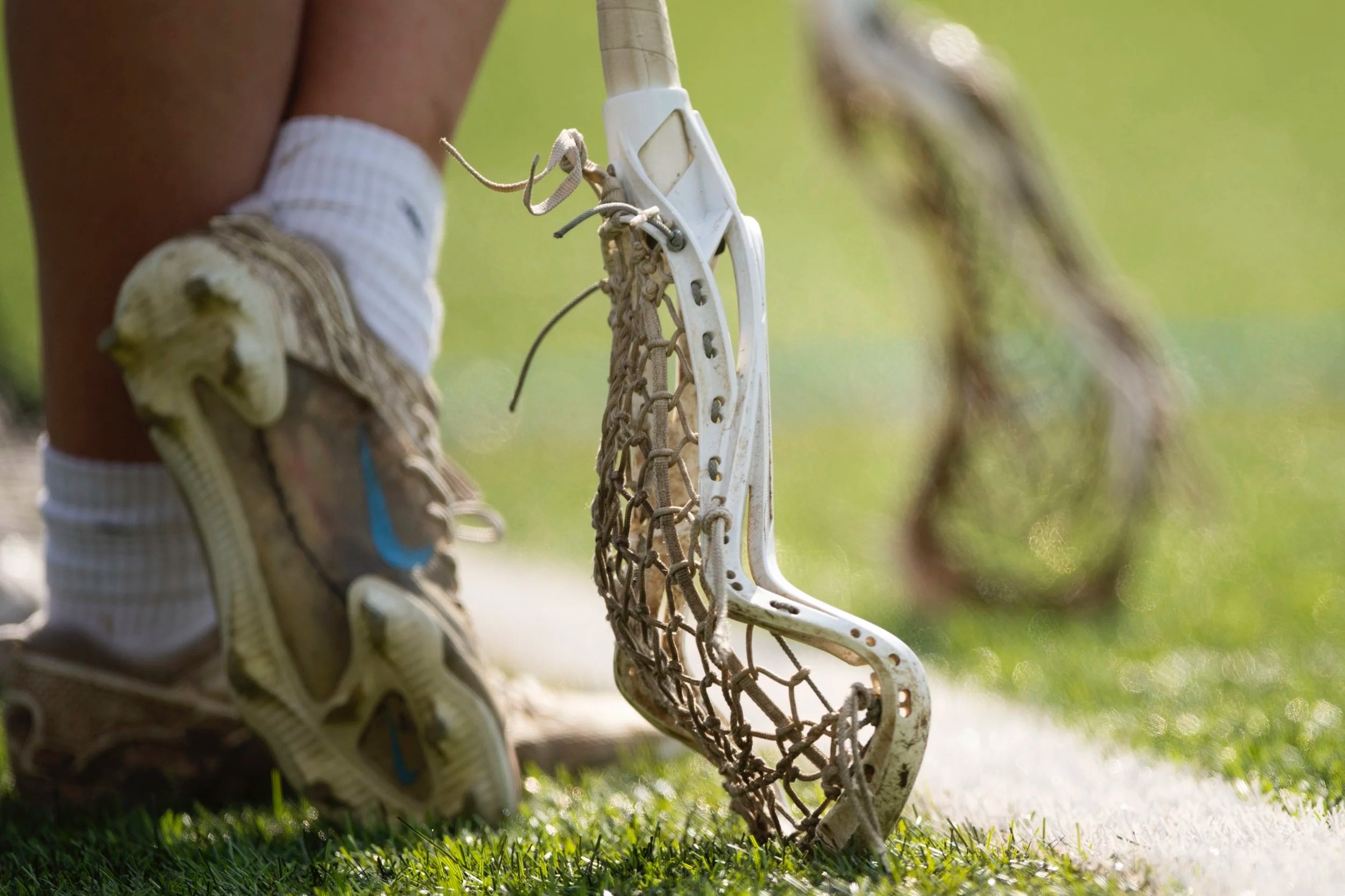 Lacrosse stick with players feet behind