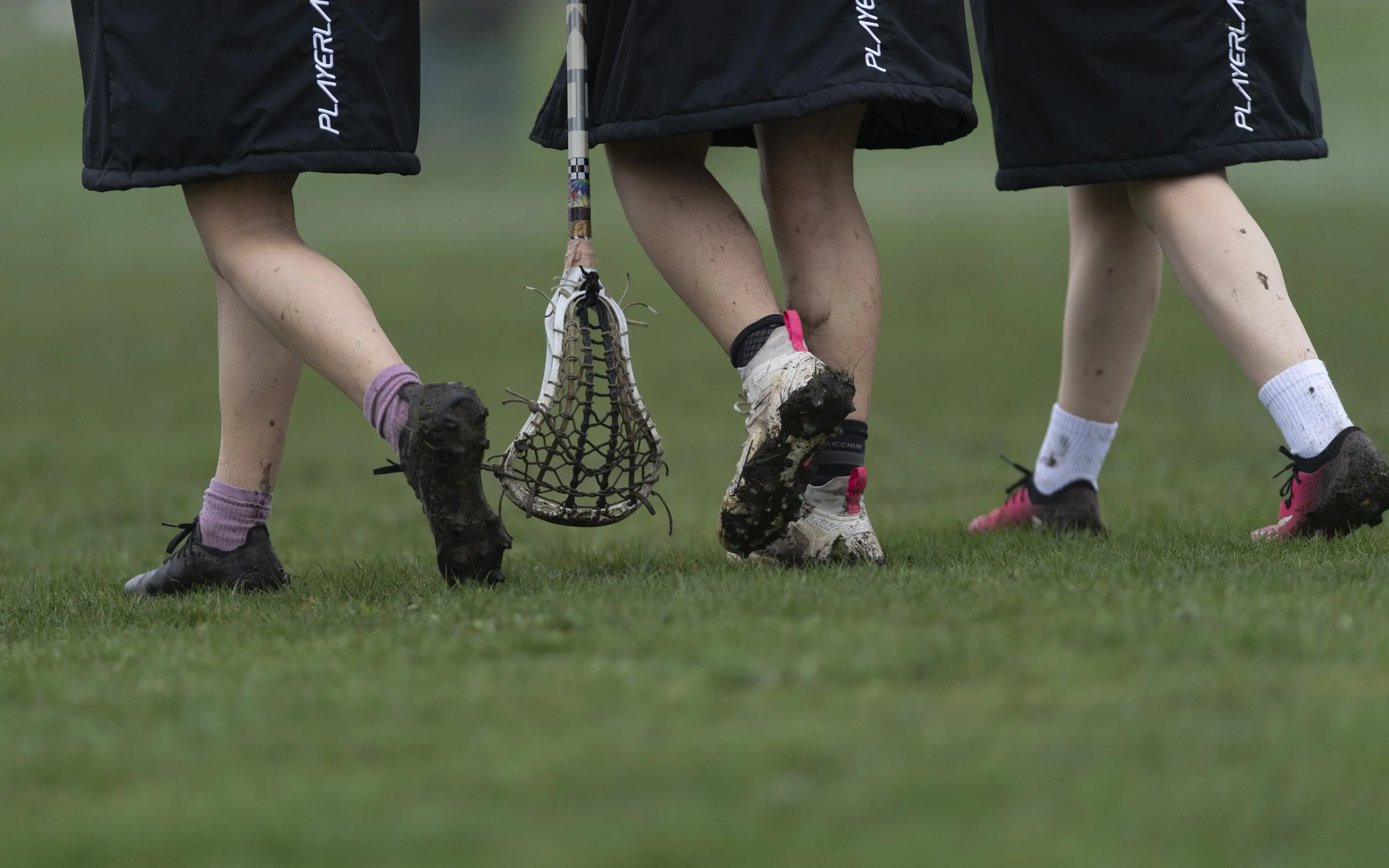Players' feet with a lacrosse stick head