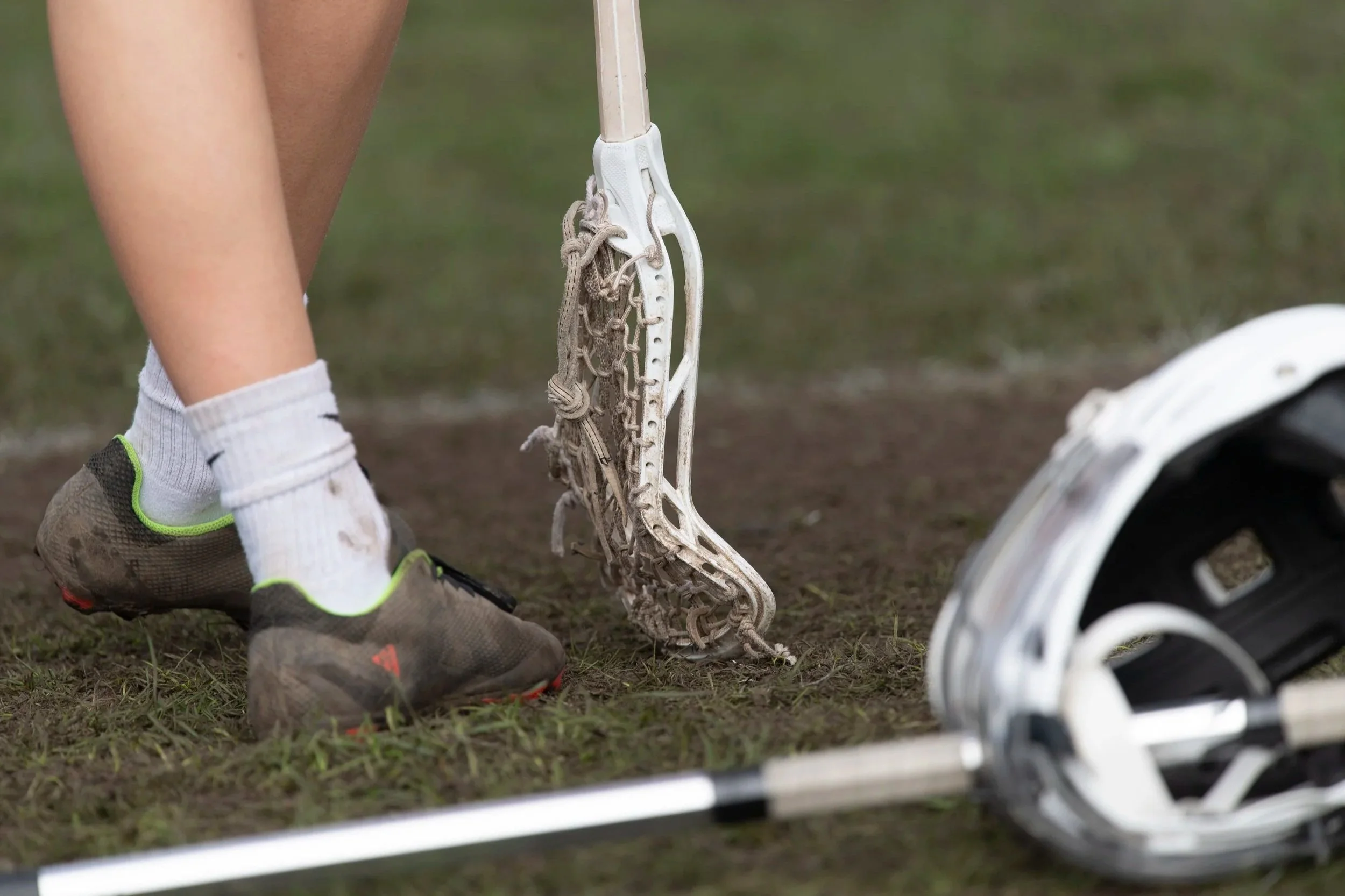 Close up of lacrosse stick next to player's legs