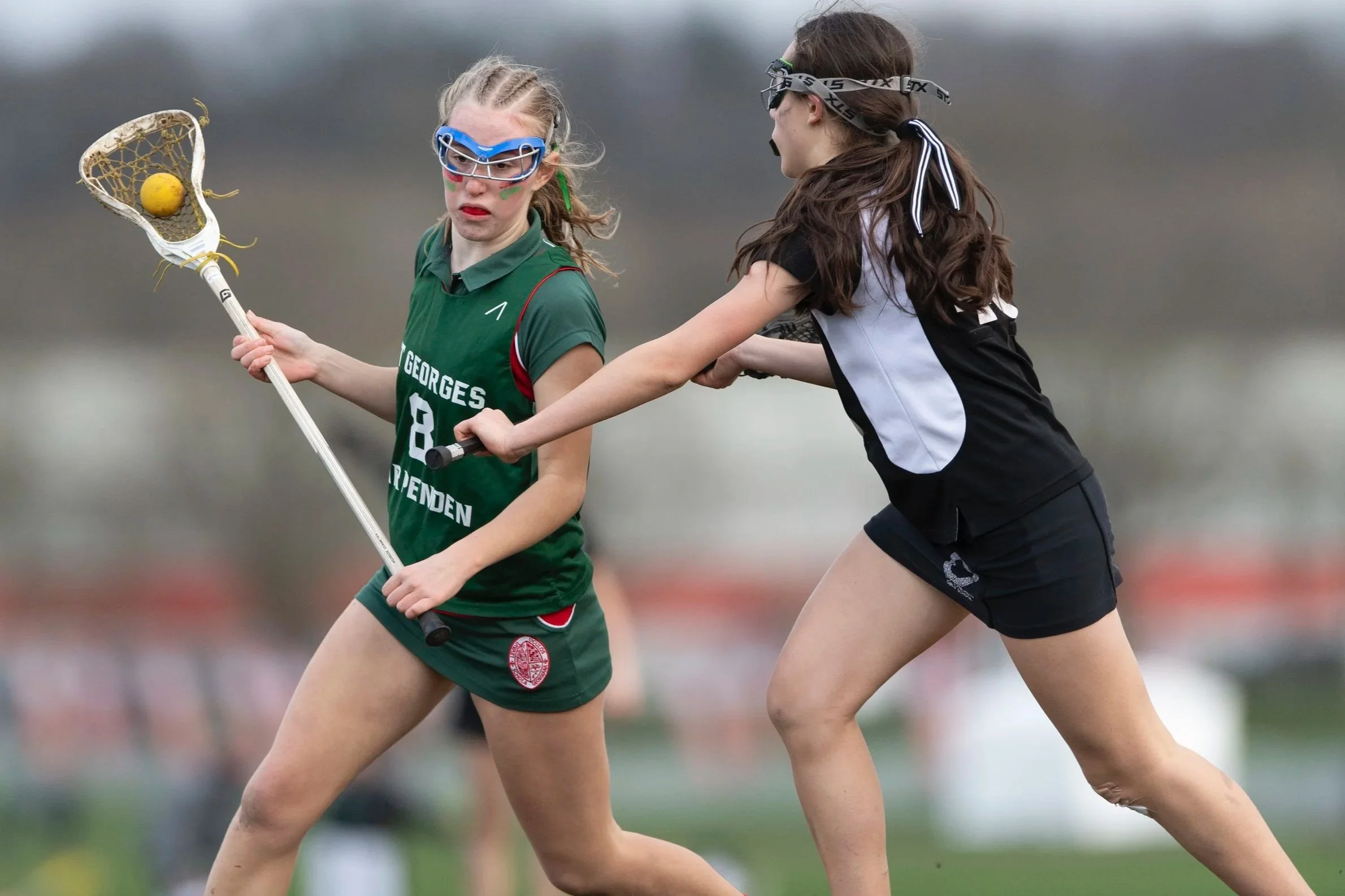 St George's player with ball in stick and opposition player defending against her