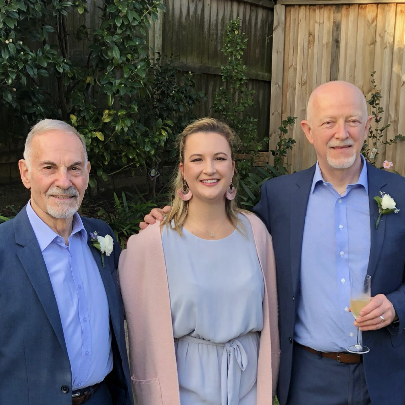 Two grooms with celebrant Married By Leah between them on their wedding day.