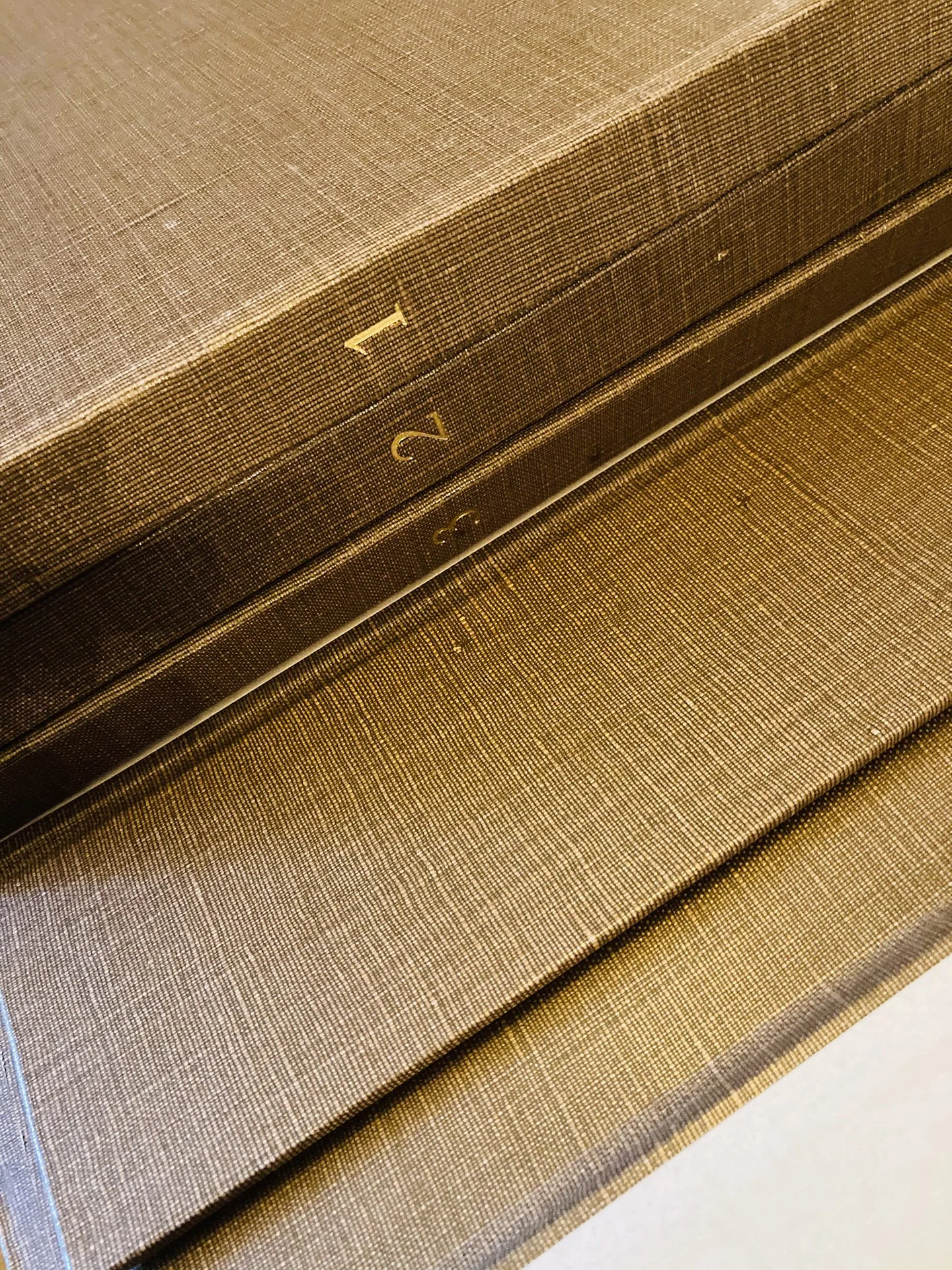 Stack of brown hardcover books with numbered spines: 1, 2, 3.