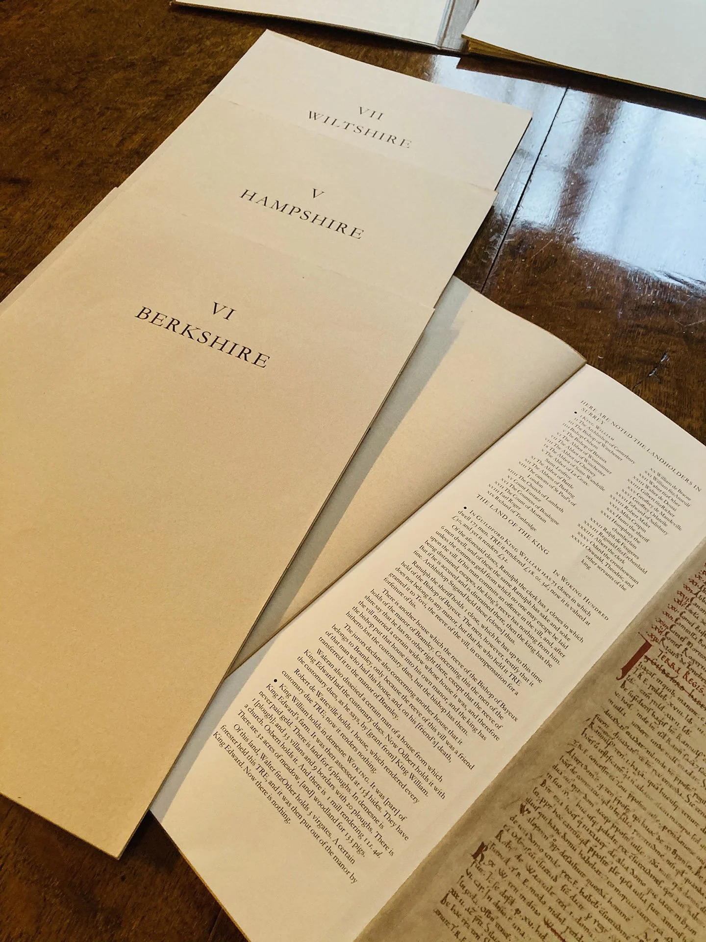 Open pages of historical documents labeled Wiltshire, Hampshire, Berkshire on a wooden table.